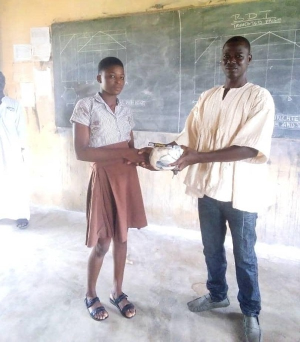 Abdul Wahab hands over a mathematical set and a ball to a BECE candidate