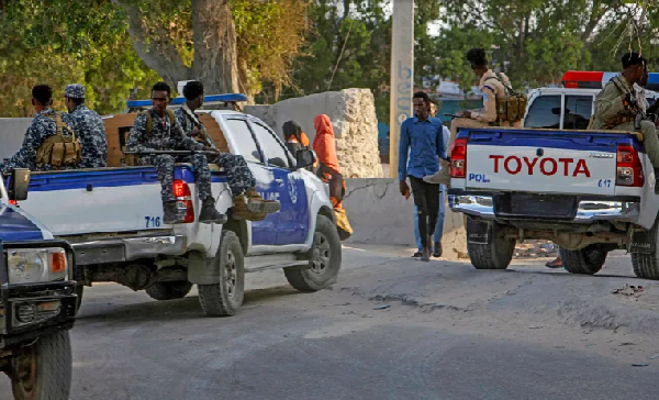 Somali police patrol near the scene of a suicide bomber attack at a cafe in Mogadishu, Somalia