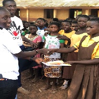 A staff of Charity Z handing over a book to a student