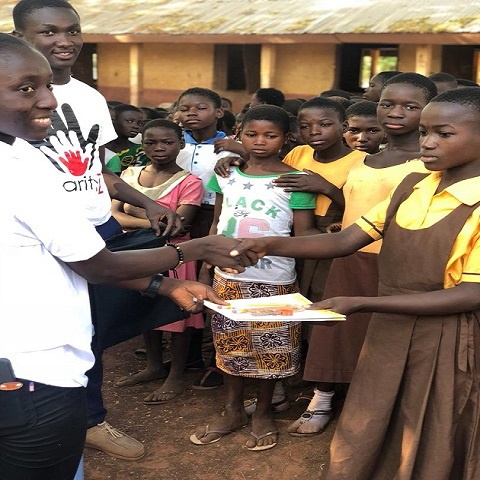 A staff of Charity Z handing over a book to a student