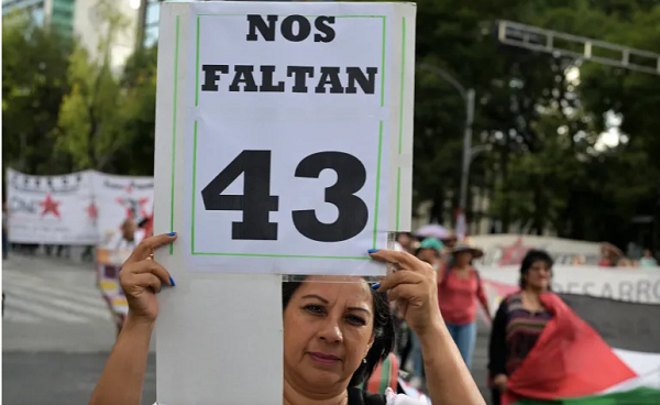 A woman holds a banner that reads 'We have 43 missing' in Spanish