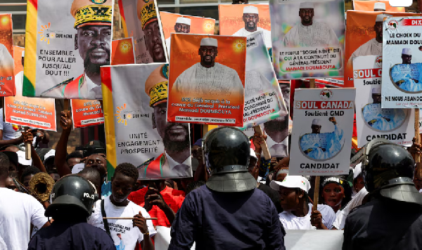 Police officers stand guard in front of supporters of Guinean leader Mamadi Doumbouya