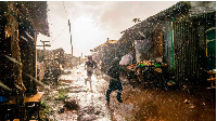 Boys running though a market during a rainfall in Kenya.