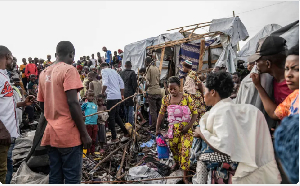 People gather around the site of an explosion in a camp for displaced people on outskirts of Goma