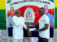 Kwasi Bonzoh presenting a cheque to one of the beneficiaries