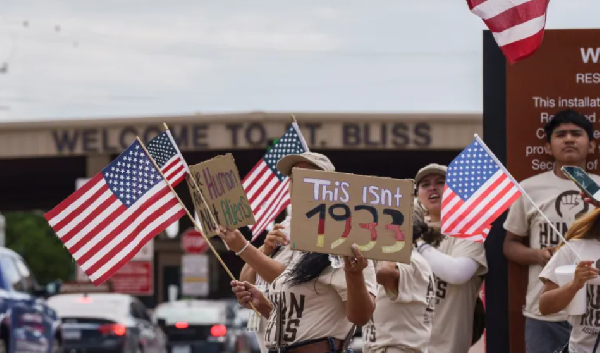 Protesters opposing mass deportations by ICE hold signs during a protest