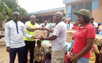 Items donated include a bag of maize, bags of sachet water, and cartons of Blue Brand margarine