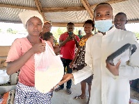 Photo of Rev Fr Emmanuel Akanzase (right) presenting some of the items to Madam Alice Ndego (left)