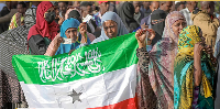 A woman displays the Somaliland flag as people queue to cast their votes during the 2024 election