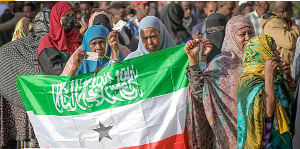 A woman displays the Somaliland flag as people queue to cast their votes during the 2024 election