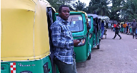 A man is seen standing beside a  tricycle