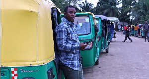 A man is seen standing beside a  tricycle