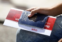 A migrant holds his passport and a train ticket