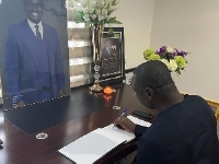 Minister of Finance, Mohammed Amin Adam, signing a book of condolence for late John Kumah