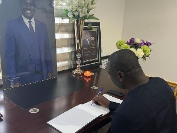 Minister of Finance, Mohammed Amin Adam, signing a book of condolence for late John Kumah