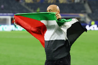 Egypt coach Hossam Hassan celebrates with a Palestine flag after the match