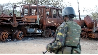 A security forces soldier walks past a burned truck at the port of Mocimboa da Praia