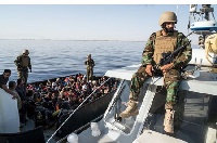 A Libyan coast guard watches over an operation to rescue illegal immigrants