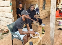 Ghana midfielder, Mubarak Wakaso (In a cap) enjoying food from wayside eatery