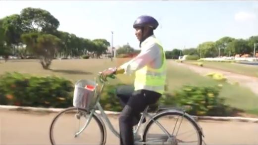 Hon. Ras Mubarak rides on a bicycle to Parliament