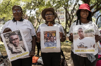 Relatives of Kenyan nationals conscripted by Russian army pose with photos of their family members