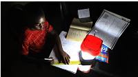 photo of a  a student doing his homework using a solar lantern in Harare, Zimbabwe