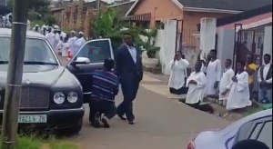 The pastor walks majestically from his car to the Church premises with his members kneeling down