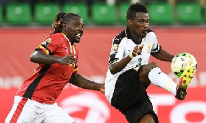 Gyan (R) challenges Uganda's midfielder Wasswa in opening game