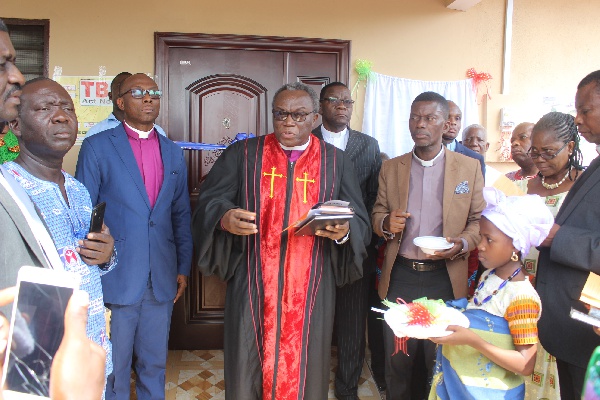 Apostle Richard Buafor [in cassock] being assisted by others to dedicate the clinic