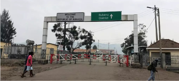 People walk past the Congo side of the Poids Lourd checkpoint at the border between Congo and Rwanda
