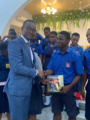 Dr Gerald Nyanyofio (L), a UPSA lecturer, presenting a book to a student