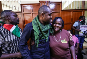 Kenyan activist Boniface Mwangi, centre, hugs Gillian Munyao, the mother of Rex Masai
