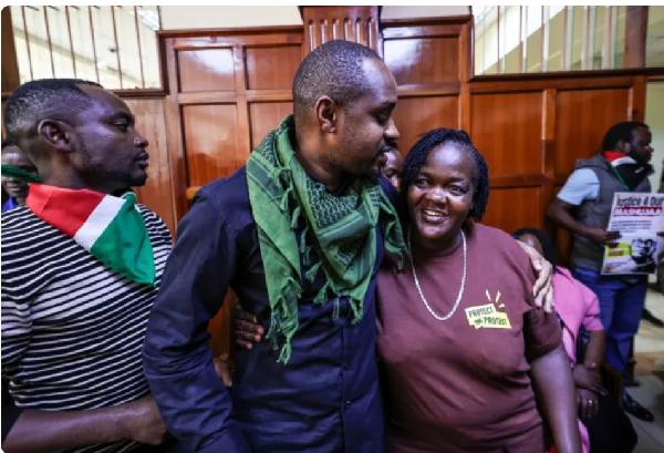 Kenyan activist Boniface Mwangi, centre, hugs Gillian Munyao, the mother of Rex Masai