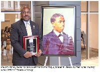 Anthony Wutoh holds his award as he stands by a portrait of Edward Bouchet