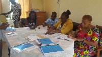 DCE for Nadowli-Kaleo, Katherine T Lankono signing documents with other members of the assembly