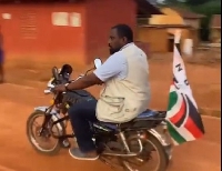 John Dumelo riding a motorcycle in Assin North