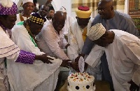 The Chief Imam being assisted to cut the birthday cake