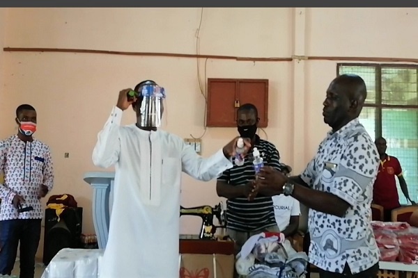Kwasi Bonzoh presenting items to one of the Senior High Schools