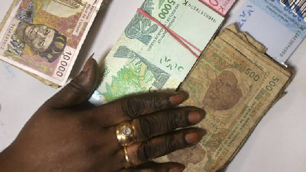 A bank teller counts new West African CFA Franc banknotes plus old-style 500 CFA notes