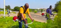 John Mahama clearing  overgrown weeds along a road