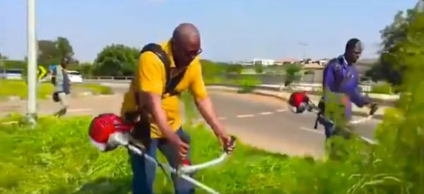 John Mahama clearing  overgrown weeds along a road