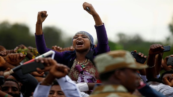 Demonstrators chant slogans while flashing the Oromo protest gesture during Irreecha