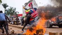 A supporter of  Bobi Wine carries his poster as they protest against his arrest PHOTO | AFP