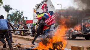 A supporter of  Bobi Wine carries his poster as they protest against his arrest PHOTO | AFP