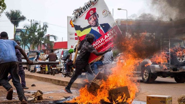 A supporter of  Bobi Wine carries his poster as they protest against his arrest PHOTO | AFP