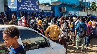 People displaced by the conflict in Sudan gather outside a passport office in the city of Gedaref