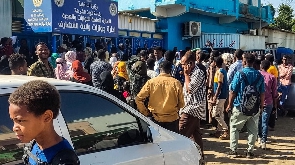 People displaced by the conflict in Sudan gather outside a passport office in the city of Gedaref