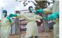 Health workers who are members of the safe and dignified burial team prepare to bury a body