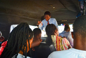A preacher stretches out his hand to pray for passengers in a trotro