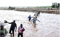 People wade through floodwaters in the aftermath of Tropical Cyclone Freddy southern Malawi
